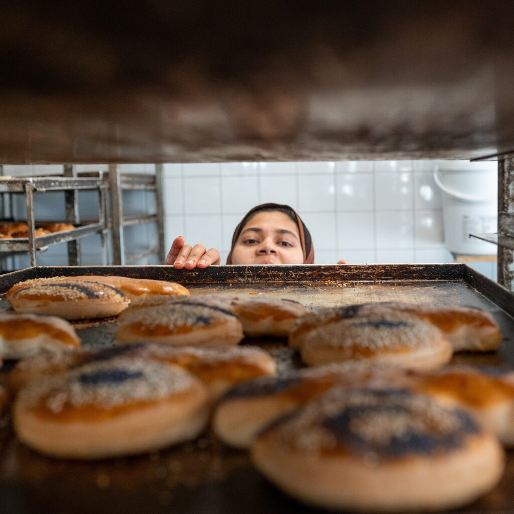 Bakker kijkt over de bakplaat de oven in